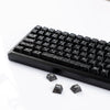 A close-up view of black carbon fiber texture keycaps for MX Mechanical keyboards lying on a white surface.
