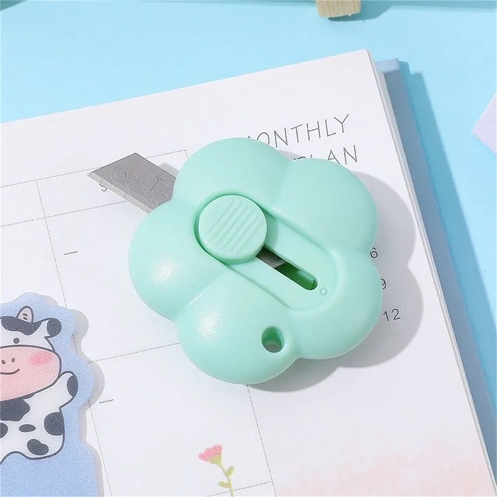 A light green floral design letter opener and paper cutter tool resting on a monthly planner page.