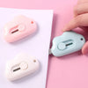 A hand holds a light pink portable utility knife next to a light blue one on a white background.