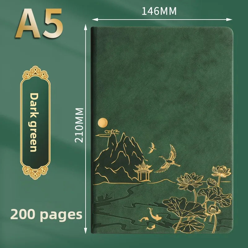 A dark green A5 notebook with gold foil illustrations of mountains, birds, and flowers on the cover.