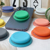 A collection of colorful silicone magnetic phone grips and stands arranged on a white surface.
