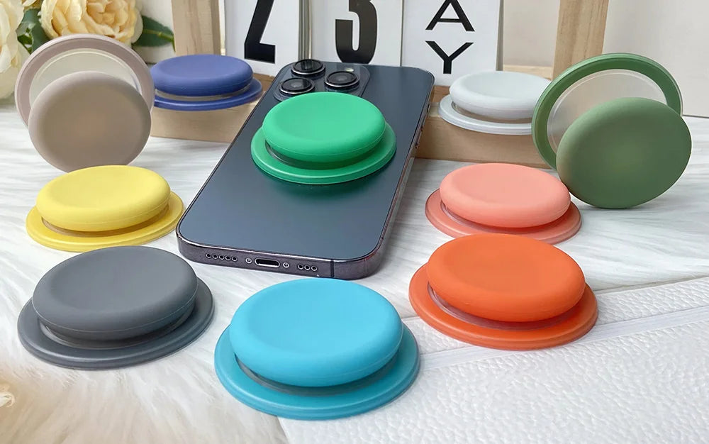 A collection of colorful silicone magnetic phone grips and stands arranged on a white surface.
