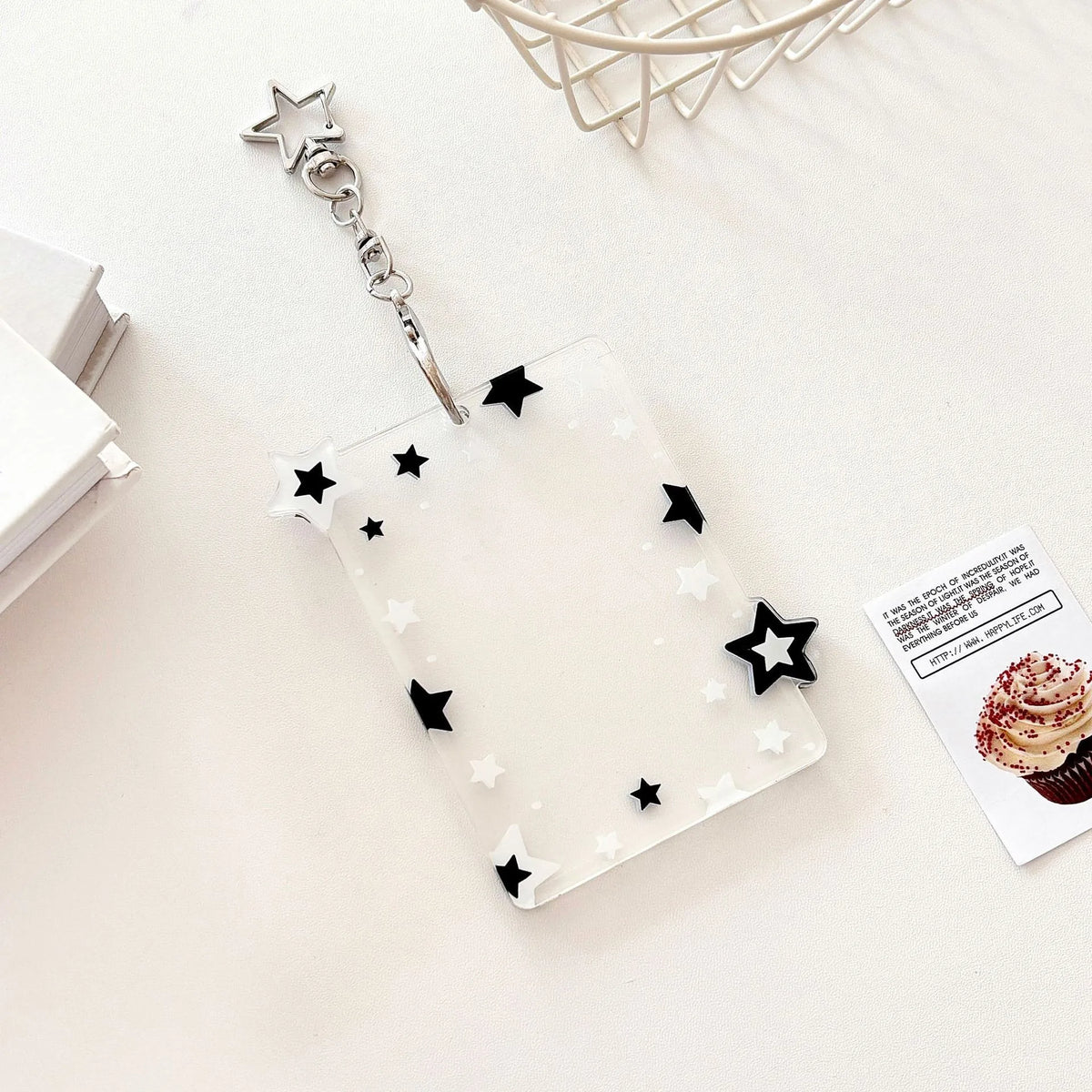 Pendentif de porte-photo en acrylique clair avec chaîne argentée et charms étoiles noir et blanc sur une surface blanche.