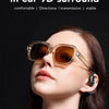 A woman is wearing transparent sunglasses and open-ear wireless earbuds while looking upwards.