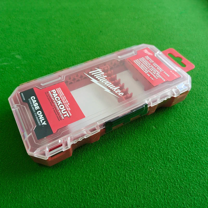 A clear plastic storage case for a Milwaukee impact driver accessory, resting on a green surface.