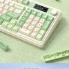 A close-up view of a light green wireless gaming keyboard with customizable keycaps and a separate switch shown nearby.
