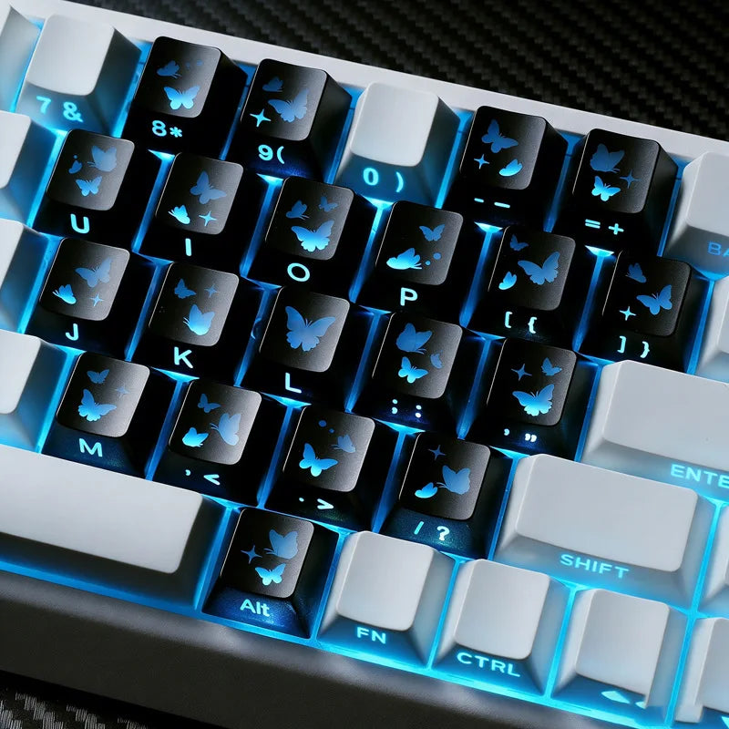 Nahaufnahme einer mechanischen Tastatur mit personalisierten Schmetterling-Keycaps und blauem LED-Licht.