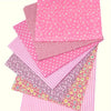 A stack of pink cotton patchwork fabric squares with various patterns including polka dots and stripes.