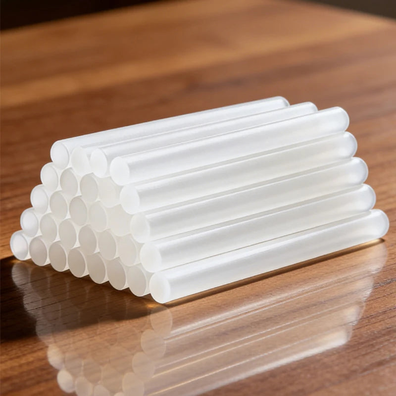 A set of white hot melt glue sticks arranged in a neat row on a wooden surface.