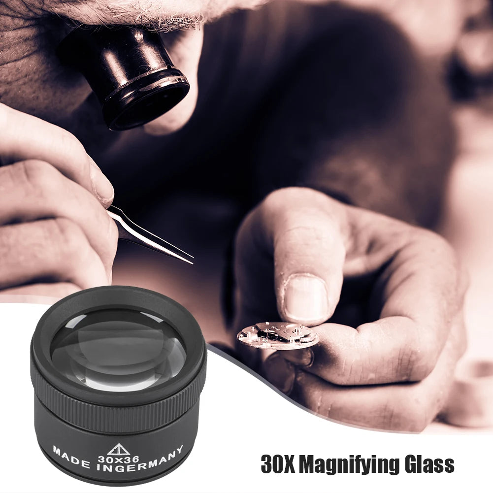 A hand holds a 30X magnifying glass over a surface, inspecting a small object.
