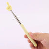 A hand holds a yellow retractable teacher pointer stick with a finger shape on the tip.