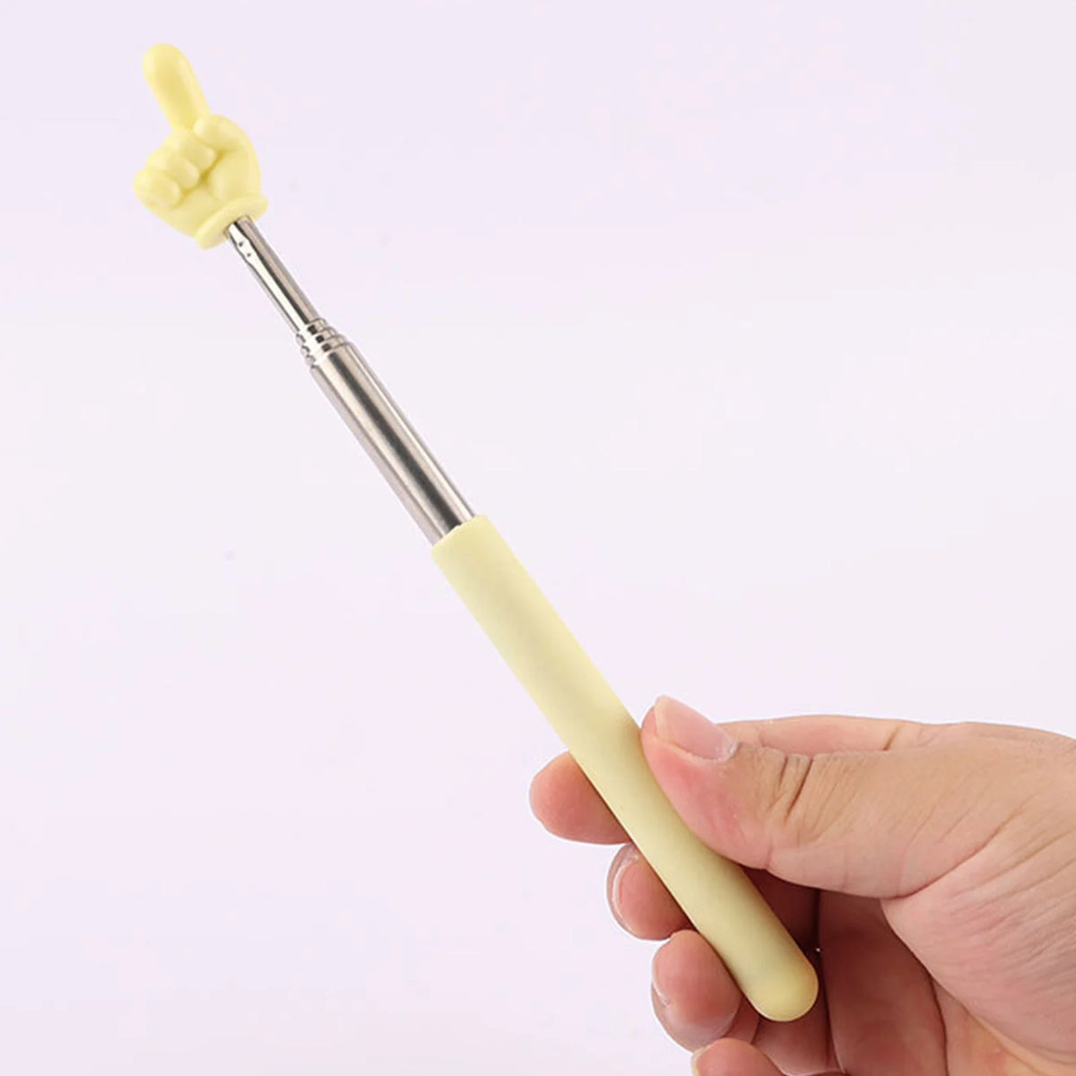 A hand holds a yellow retractable teacher pointer stick with a finger shape on the tip.
