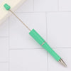 A bright green DIY beadable pen with a silver tip and a metal cap resting on a white tiled surface.