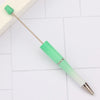 A green DIY beadable pen with a silver clip is shown lying on a white surface.