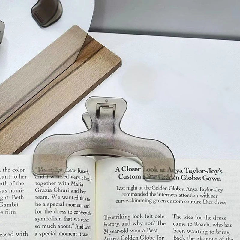 A close-up of frosted transparent book page clips resting on a white surface.