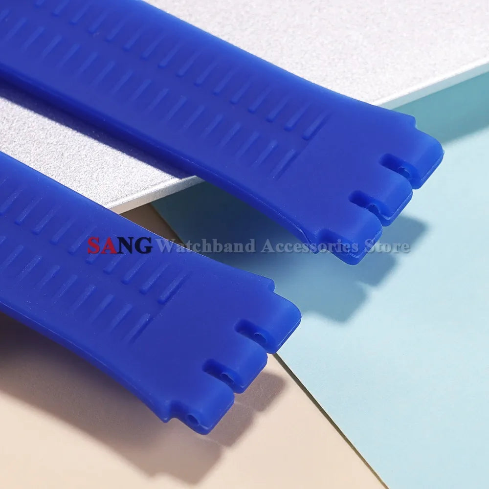 A close-up view of a blue silicone watchband with replacement tools lying on a light surface.
