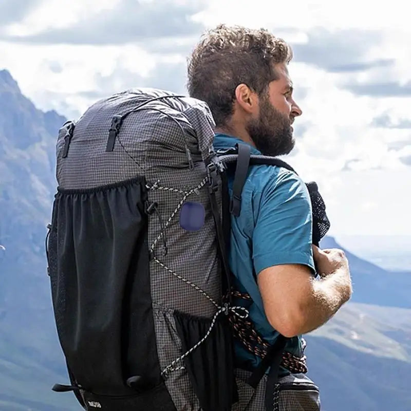 A man wearing a blue shirt and backpack looks out over a scenic landscape.