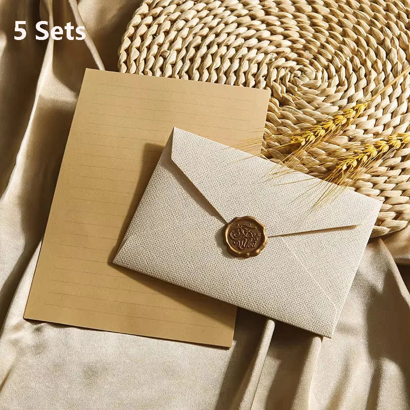 Fünf Sets beige Leinenumschläge und Briefe mit Wachssiegeln auf einer geflochtenen Matte.