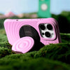 A pink Ripple Grip magnetic phone stand with a silicone finish resting on green moss.