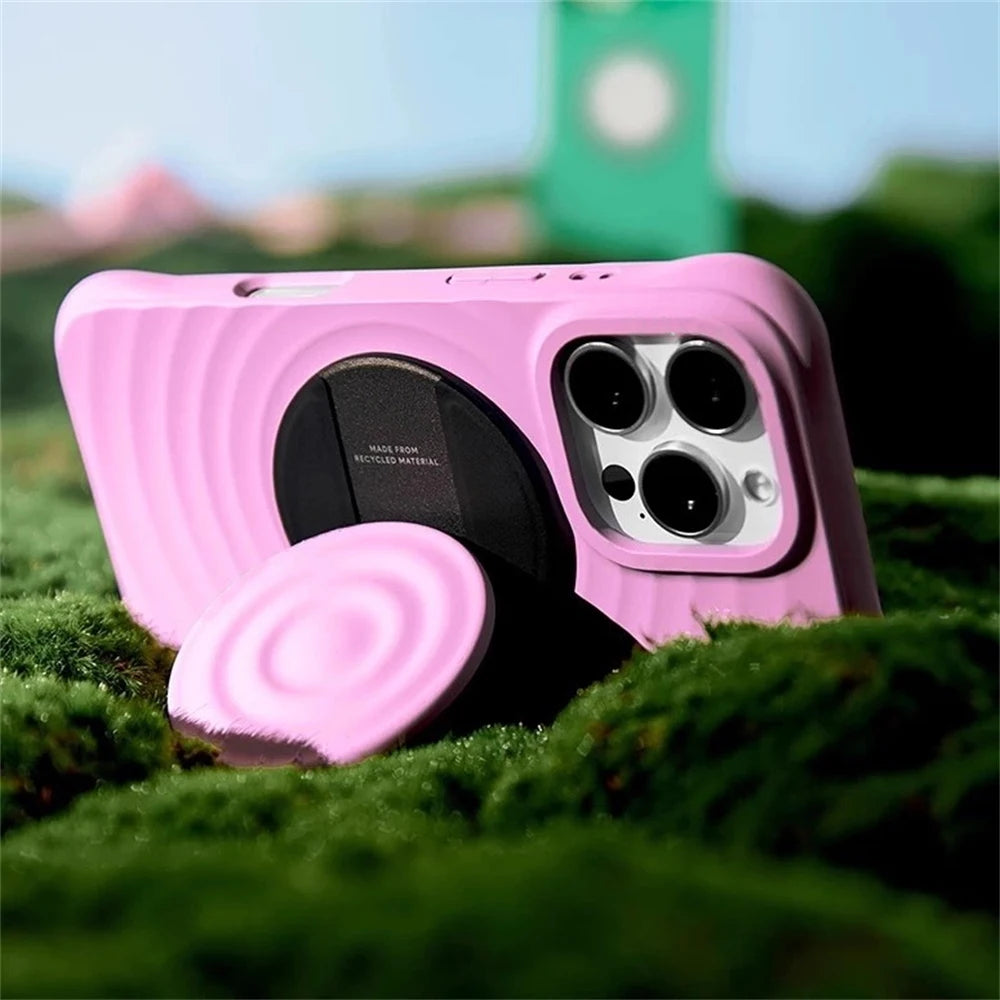 A pink Ripple Grip magnetic phone stand with a silicone finish resting on green moss.
