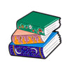 An enamel lapel pin depicting a stack of three books with vibrant green, pink, and blue covers.