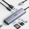 محوّل USB-C فضي متعدد المنافذ مزود بـ HDMI و Ethernet وتوصيل الطاقة ومنافذ توسيع متنوعة.