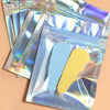 A stack of holographic rainbow pattern sealing bags containing blue and yellow stickers.
