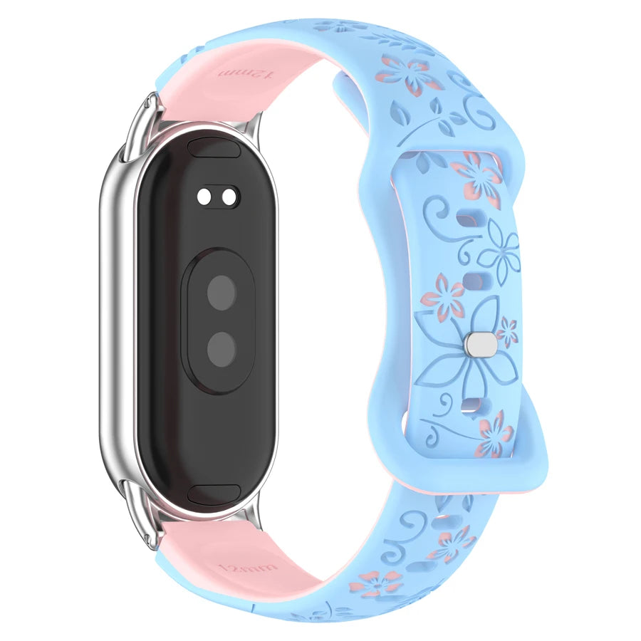A light blue silicone watch band with pink floral engravings and a silver casing for a smart band.