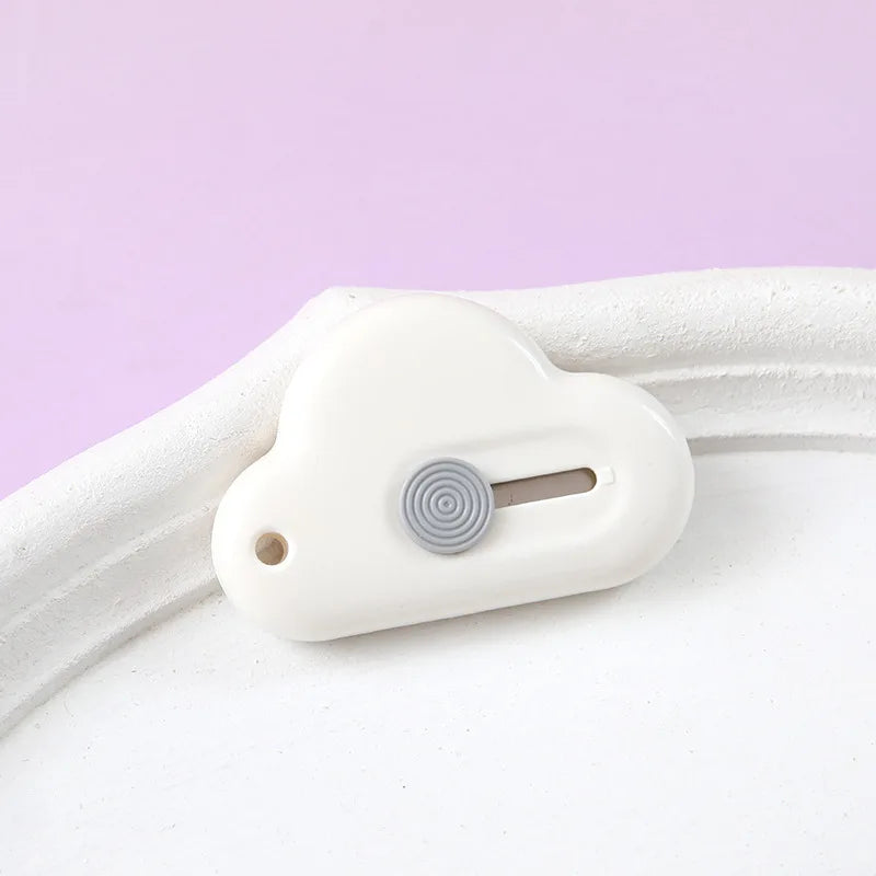 A white portable utility knife with a round silver blade is shown resting on a white surface.