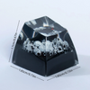 A black resin keycap shaped like a gothic raven with a skull design.