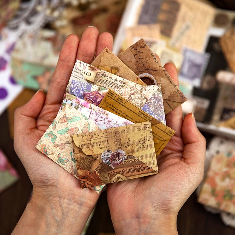 يد تمسك بمجموعة من ملصقات والمستلزمات الورقية القديمة والديكورية.