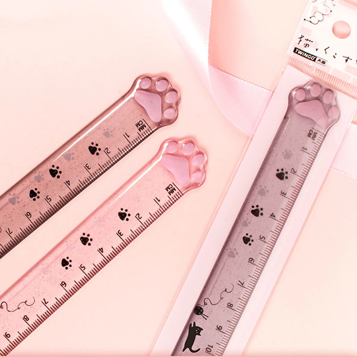 A pink plastic measuring tool shaped like a cat paw, used for measuring, is shown against a light background.