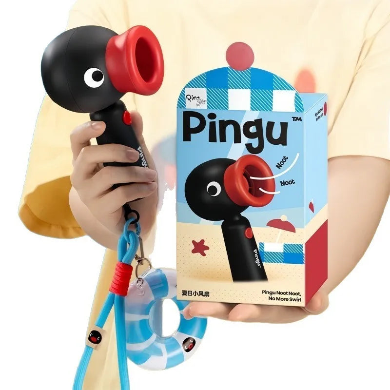 A hand holds a Pingu penguin rechargeable handheld fan with a rotating head and a blue strap.