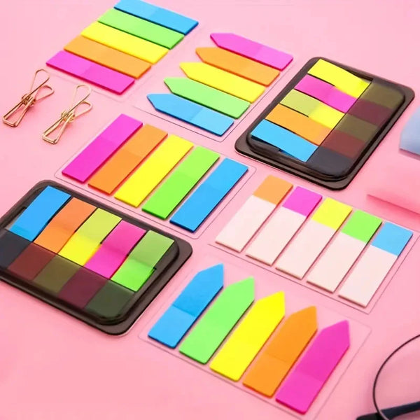 A collection of fluorescent PET sticky notes with index tabs arranged in various colors on a pink background.