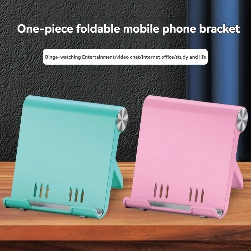 Two one-piece foldable mobile phone brackets in teal and pink colors displayed on a wooden surface.