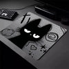 A black cat silhouette design on a mouse pad with a non-slip rubber base, next to a keyboard.