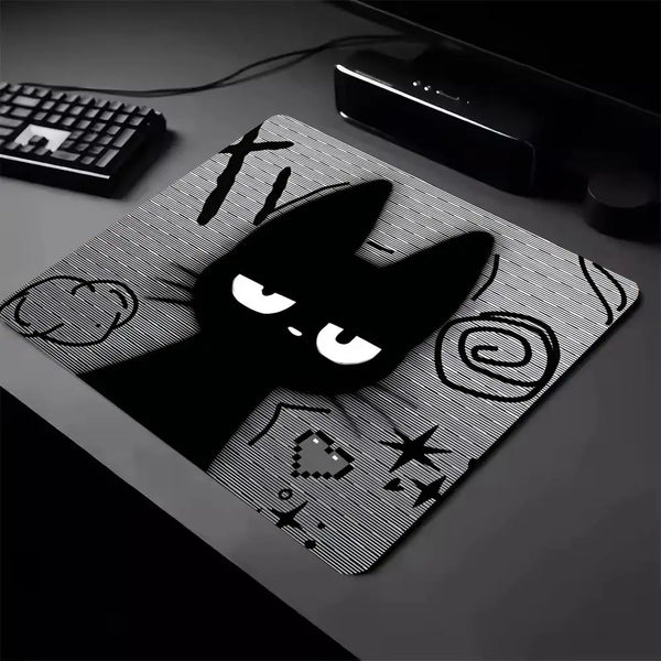 A black cat silhouette design on a mouse pad with a non-slip rubber base, next to a keyboard.