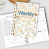A weekly planner notebook with a floral design and habit tracker pages is shown on a light gray background.