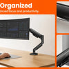 A person working at a desk with a monitor mounted on a fully adjustable monitor arm.