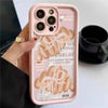 A pink phone case with a croissant newspaper pattern is held by a hand next to a black mug.