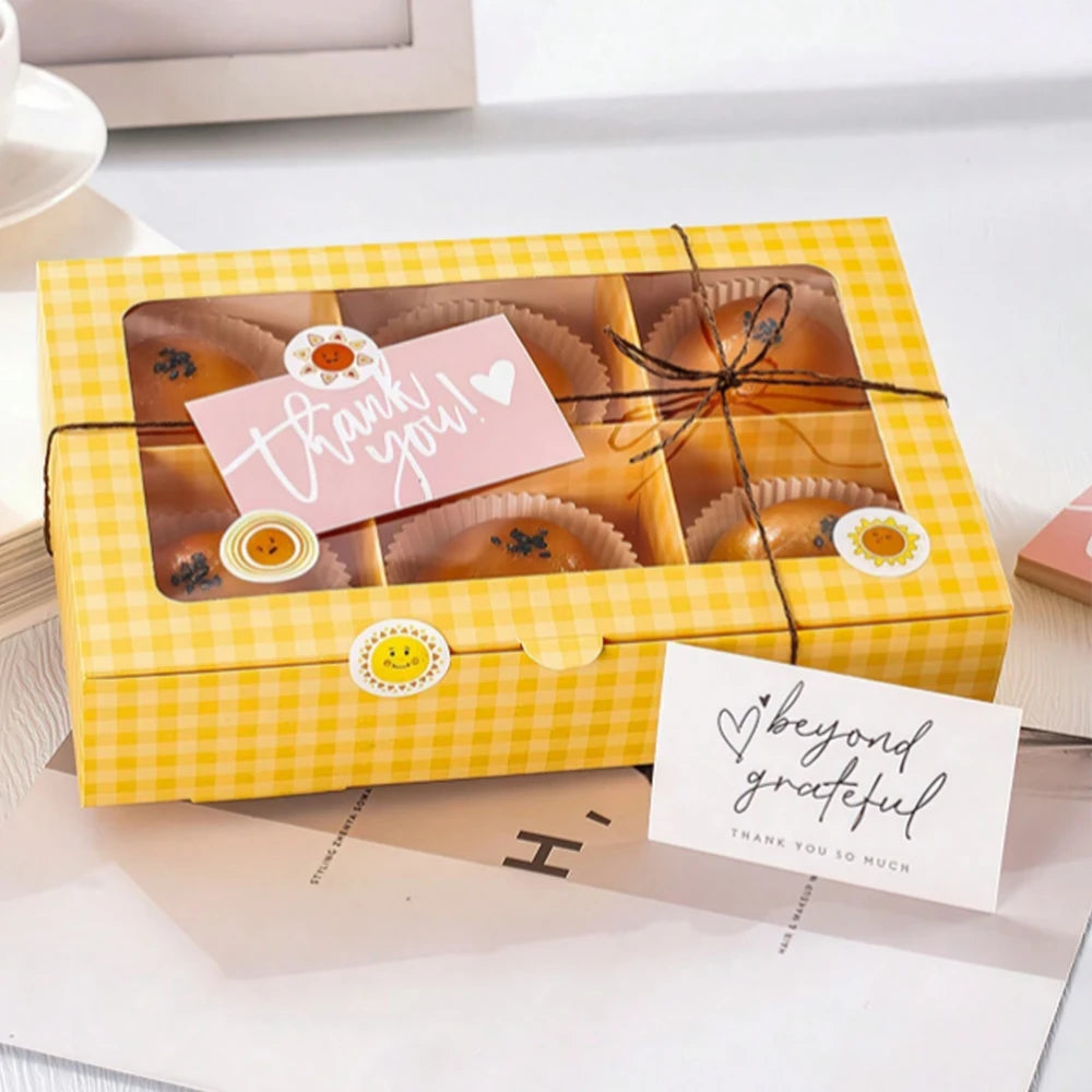 A yellow gift box filled with thank you cards, featuring a honeycomb pattern and a pink thank you note.