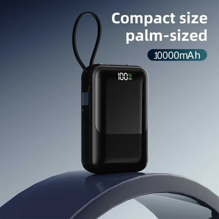 Batterie portable noire de la taille d'une paume, avec indicateur de batterie et boucle flexible, sur une surface bleue.