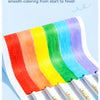 A set of silky crayons in a rainbow gradient color palette shown on white paper.