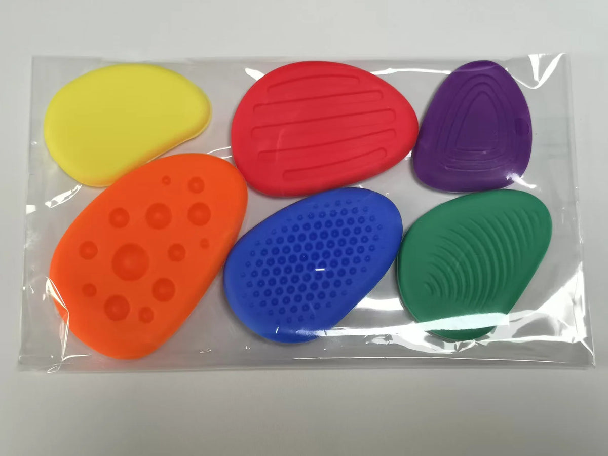 A clear plastic box containing five brightly colored silicone sensory stones for fidget relief