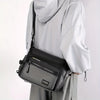 A woman is holding a black and gray multifunctional crossbody bag under a white hoodie.