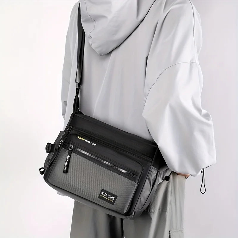 A woman is holding a black and gray multifunctional crossbody bag under a white hoodie.
