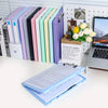 A collection of colorful A4 document and photo storage file boxes lined up next to a laptop and a box of flowers.