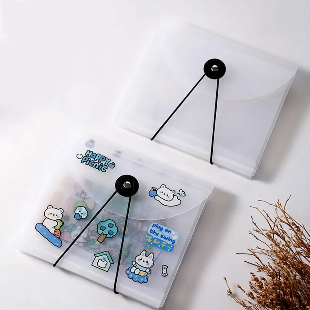 A clear plastic storage book with black elastic bands is shown, featuring a cute bear sticker on the cover.