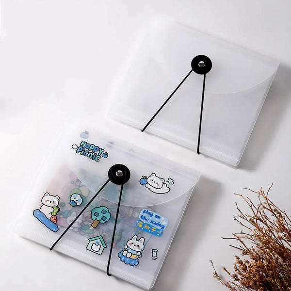 A clear plastic storage book with black elastic bands is shown, featuring a cute bear sticker on the cover.