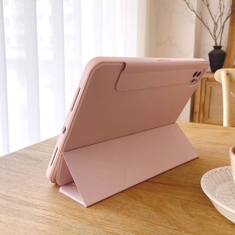 A pink magnetic protective case for an iPad, shown open on a wooden table.